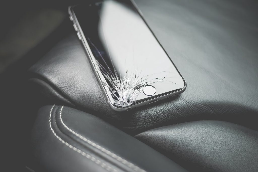 Persoon twijfelt tussen repareren of weggooien van een beschadigde smartphone